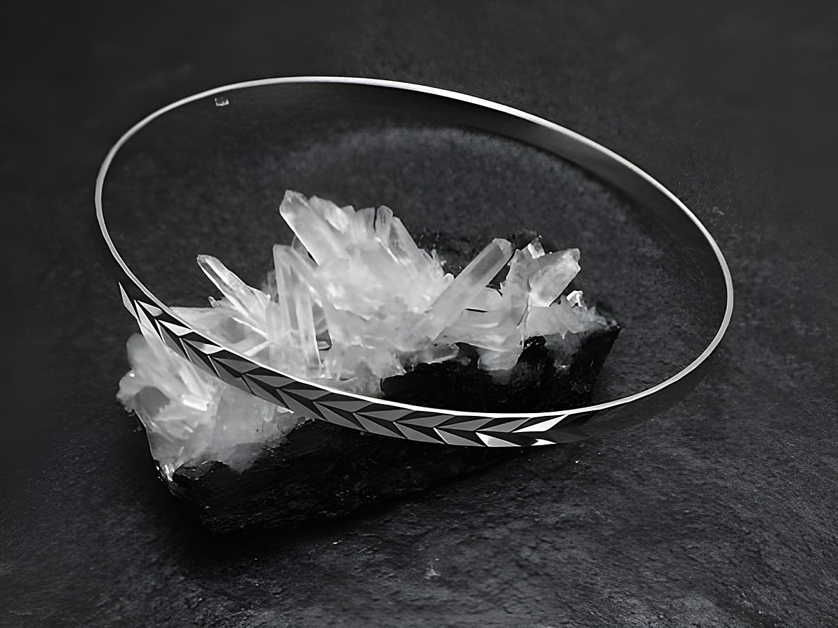 Silber Armreifen im 70er Design, rhodiniert, 3,5 mm dick und 21 cm lang, von Juwelier Harnisch, auf Kristallbasis präsentiert, betont durch einen eleganten und zeitlosen Stil.