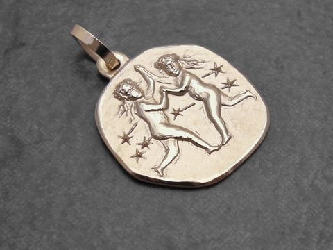 Ein goldener Anhänger mit dem Sternzeichen Zwillinge, der zwei tanzende Figuren und Sterne zeigt, hergestellt vom Juwelier Harnisch, ideal für Liebhaber astrologischer Schmuckstücke.