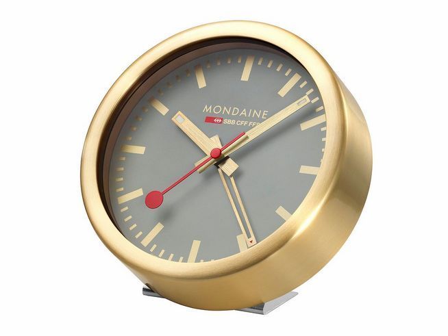 Eleganter Mondaine A997.MCAL.86SBG.1 Wecker in mattiertem, vergoldetem Aluminium mit grauem Ziffernblatt und roten Akzenten, Durchmesser 12,5 cm, ideal für stilbewusste Räume.