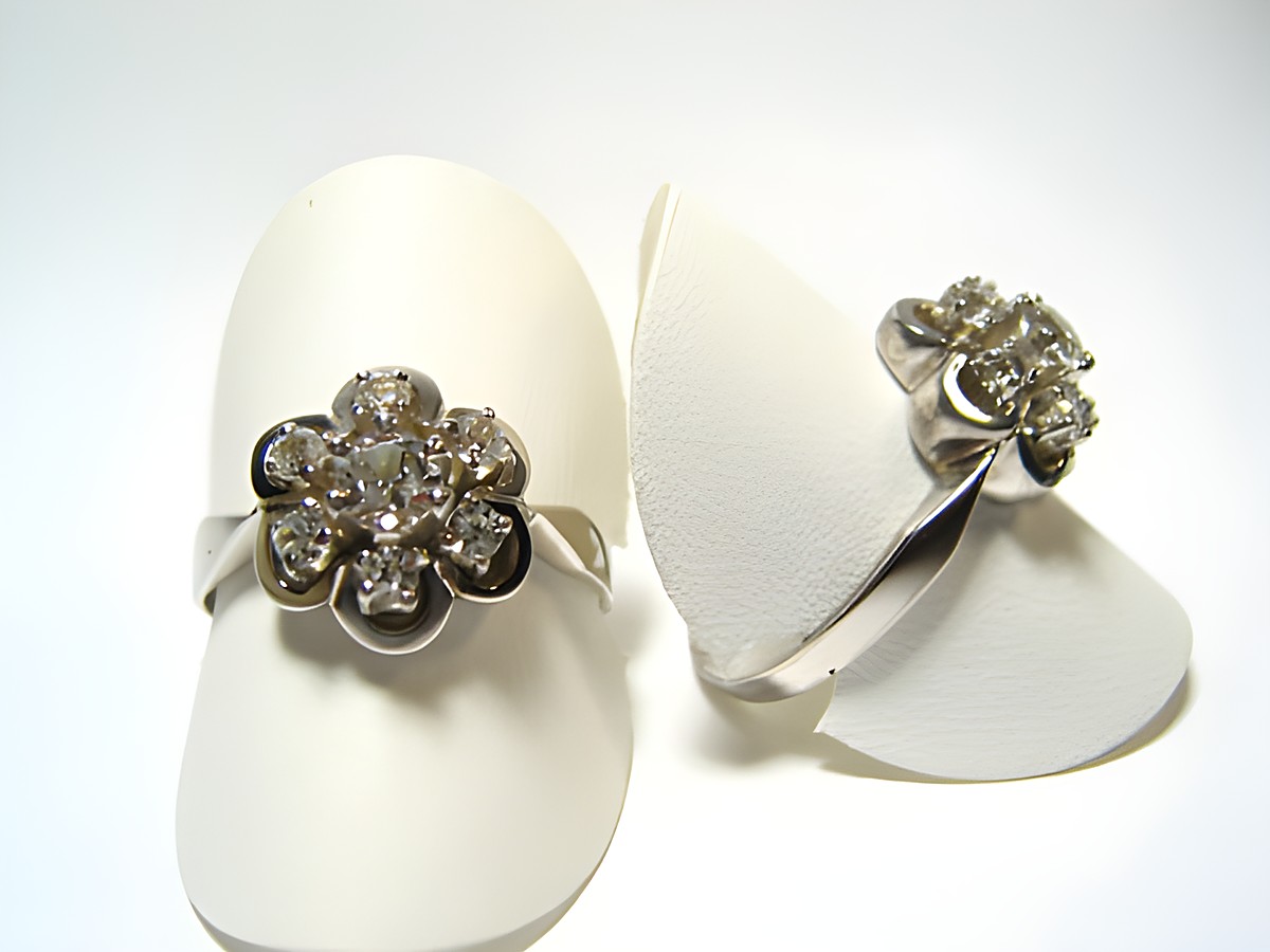 Silber Ring rhodiniert mit weiß gefassten Steinen, Hersteller Juwelier Harnisch, verstellbare Ringe in floraler Form auf weißem Hintergrund.