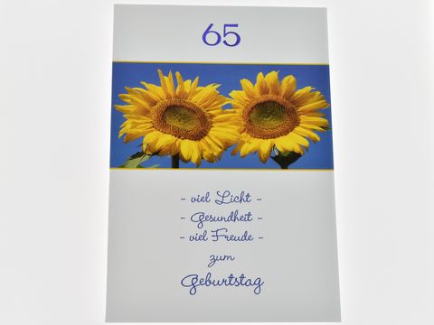Geburtstagskarte mit zwei sonnigen Sonnenblumen auf blauem Hintergrund, der Text wünscht viel Licht, Gesundheit und Freude zum 65. Geburtstag, hergestellt von Juwelier Harnisch.