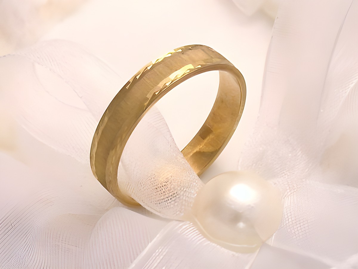 Trauring Ehering aus Gold 333 in Gr. 57/18,1 von Juwelier Harnisch, bis Gr. 58/18,4, schmaler Ring mit dezentem Muster, elegant drapiert auf einem zarten Stoff mit Perle.