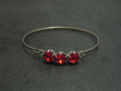 Dunkelroter Strass Armreifen mit drei funkelnden Steinen, silberfarbener Fassung, 18 cm lang und feminin gestaltet, Hersteller Juwelier Harnisch, ideal für eleganten Schmuck.