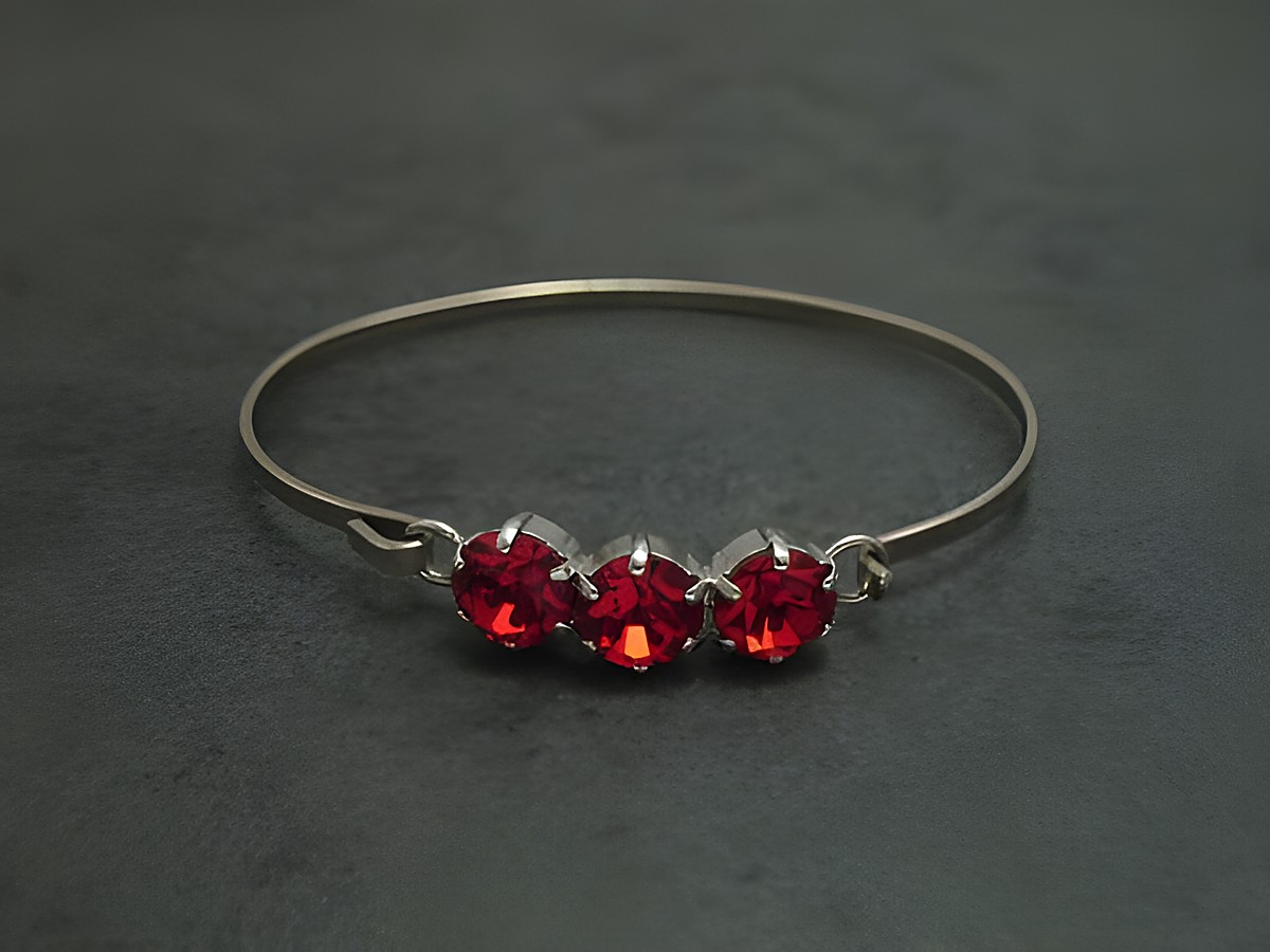Dunkelroter Strass Armreifen mit drei funkelnden Steinen, silberfarbener Fassung, 18 cm lang und feminin gestaltet, Hersteller Juwelier Harnisch, ideal für eleganten Schmuck.
