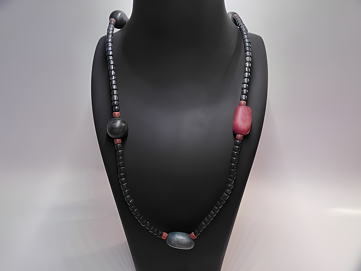 Holzkette Multiform 21 mm bunt 90 cm Holz Schmuck von Juwelier Harnisch auf einer stylischen Schmuckpuppe präsentiert, mit mehreren bunten Holzperlen in verschiedenen Formen und Farben.