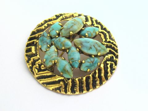 Runde Strass Brosche im türkis look gefasste Steine, Hersteller: Juwelier Harnisch, Broschen - Türkis - Look, dekorativer goldfarbener Hintergrund mit strukturiertem Muster.