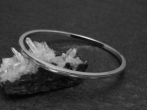 Silber Armreifen zart 3 mm rhodiniert 18 cm von Juwelier Harnisch, elegant auf einem schwarzen Hintergrund dargestellt, mit Kristallen zur Präsentation.