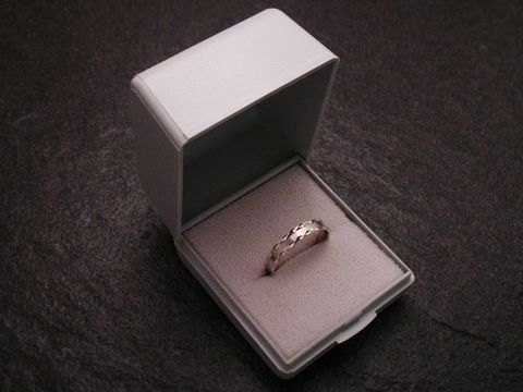 Geschenkschachtel für einen Ring in hellgrau mit den Maßen 5 cm, Hersteller Juwelier Harnisch, geöffnet mit einem Ring auf weichem Innenpolster.