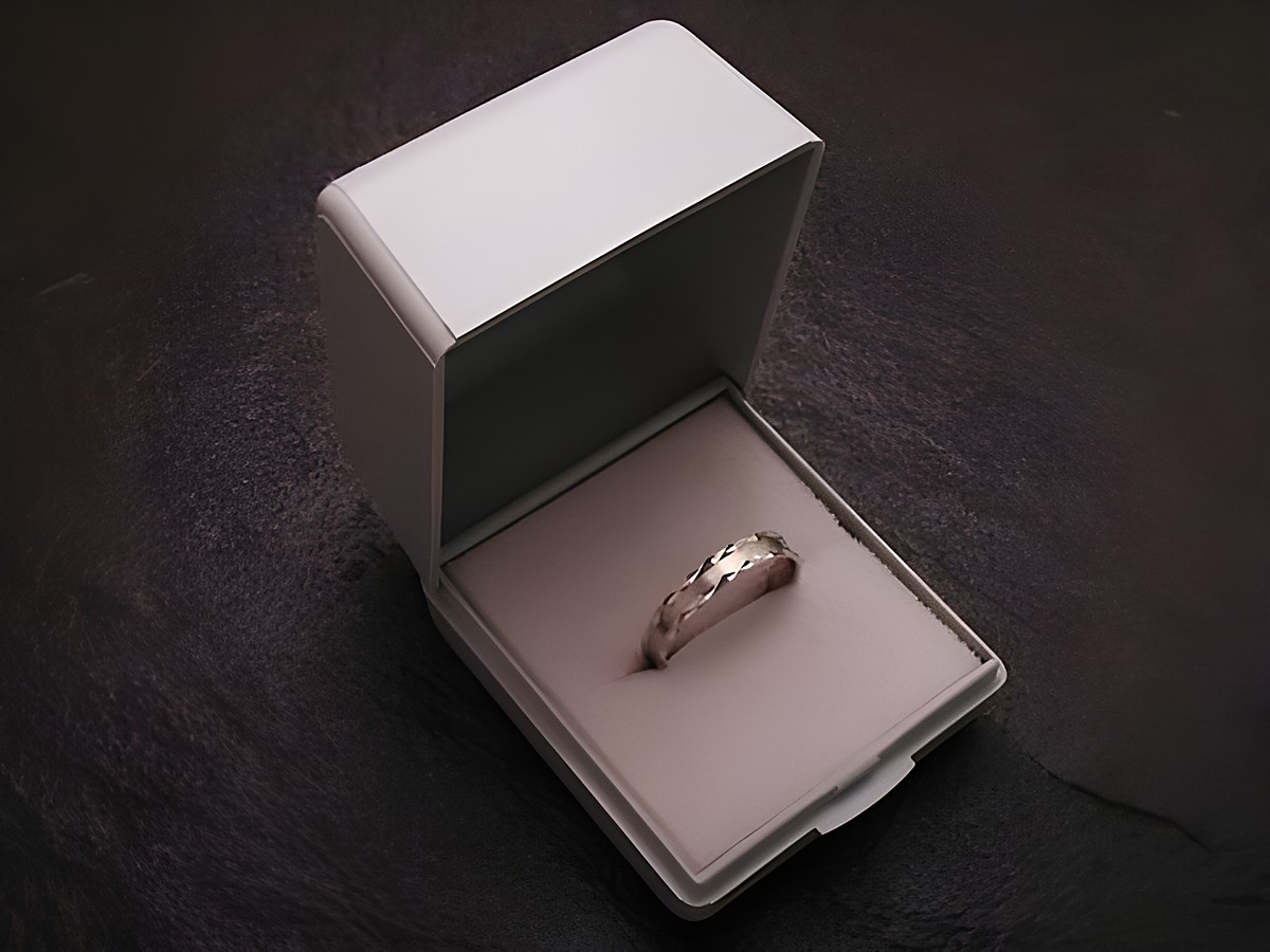 Geschenkschachtel für einen Ring in hellgrau mit den Maßen 5 cm, Hersteller Juwelier Harnisch, geöffnet mit einem Ring auf weichem Innenpolster.