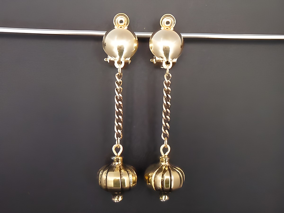 Ohrclip in zeitlosem Design, 56 mm lang, goldfarben, mit einer eleganten Kette und dekorativen Anhängern, hergestellt von Juwelier Harnisch.
