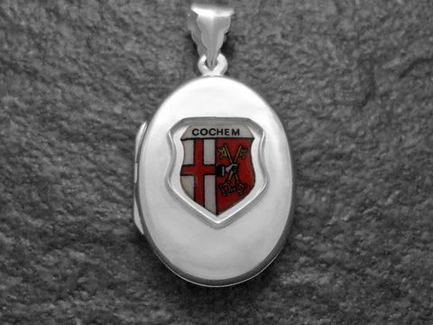 Silbernes Medaillon mit dem Stadtwappen von Cochem, Deutschland, dargestellt in einem ovalen Design. Der Hersteller ist Juwelier Harnisch aus Rheinland-Pfalz.