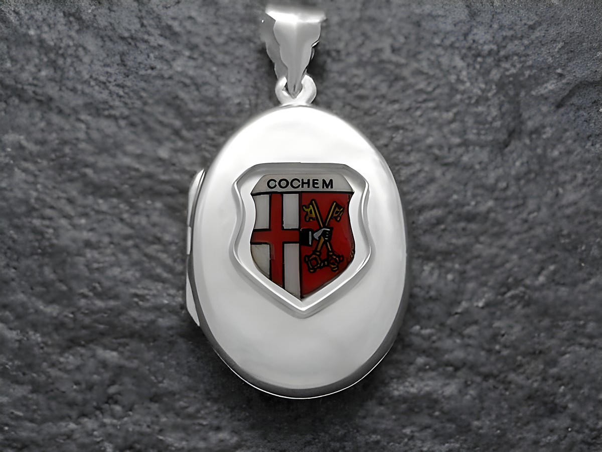 Silbernes Medaillon mit dem Stadtwappen von Cochem, Deutschland, dargestellt in einem ovalen Design. Der Hersteller ist Juwelier Harnisch aus Rheinland-Pfalz.