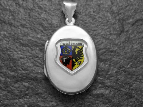 Ein silbernes Medaillon mit dem Stadtwappen von Westerland, das einen bunten Schild mit einer Krone und einem Löwen zeigt, hergestellt von Juwelier Harnisch in Schleswig-Holstein.
