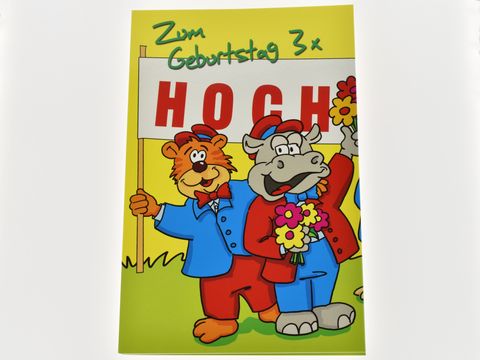 Geburtstagskarte mit bunten Tieren, die zu einem Geburtstag gratulieren. Ein Bär und ein Nashorn halten ein Schild mit der Aufschrift HOCH und Blumen in den Händen. Hersteller Juwelier Harnisch.