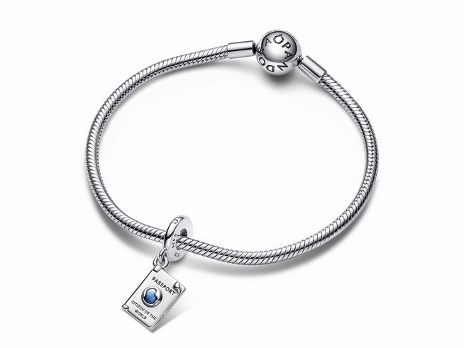 Auf dem Bild ist ein silberner Armband mit einem Aufklappbaren Reisepass Charm-Anhänger zu sehen. Der Anhänger ist von Pandora und zeigt ein attraktives Design mit blauen Akzenten.