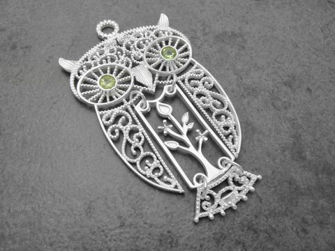 Beweglicher Silberanhänger in Form einer Eule mit Peridot-Augen und filigranem Design, symbolisiert Glück und Weisheit. Hersteller: Juwelier Harnisch.