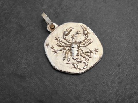 Anhänger aus Gold mit dem Motiv des Sternzeichens Skorpion, gestaltet vom Juwelier Harnisch, zeigt einen detaillierten Skorpion umgeben von kleinen Sternen.
