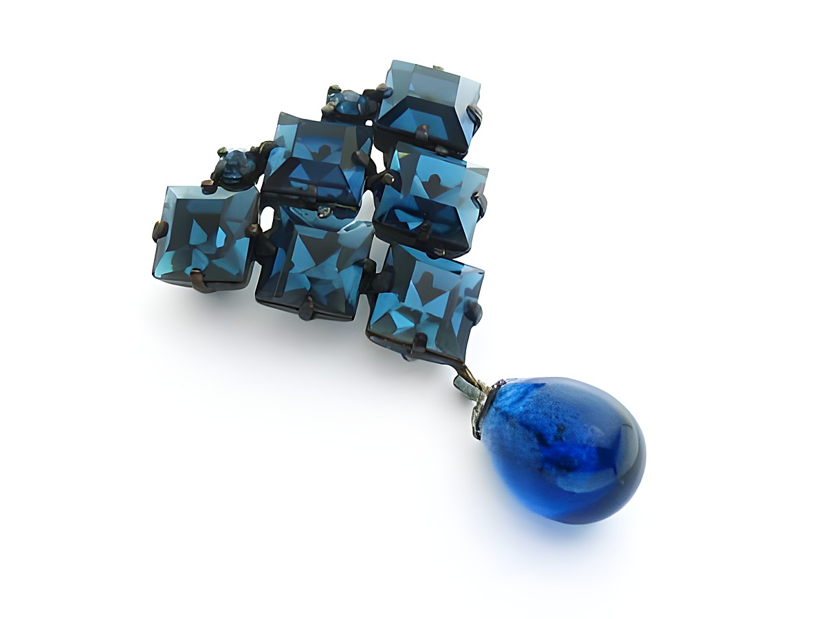 Blaue Strass Brosche im Sexy City Look mit quadratischen blauen Strasssteinen und einem tropfenförmigen, blauen Anhänger, Hersteller Juwelier Harnisch, strahlendes Design.