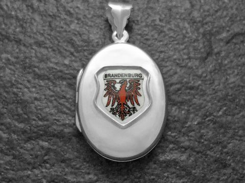 Silbernes Medaillon mit dem Wappen von Brandenburg, welches einen roten Adler zeigt, auf hellem Hintergrund. Der Hersteller ist Juwelier Harnisch aus Brandenburg.