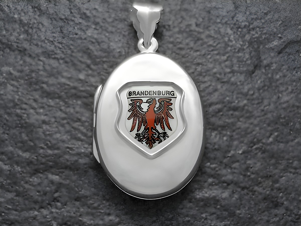 Silbernes Medaillon mit dem Wappen von Brandenburg, welches einen roten Adler zeigt, auf hellem Hintergrund. Der Hersteller ist Juwelier Harnisch aus Brandenburg.