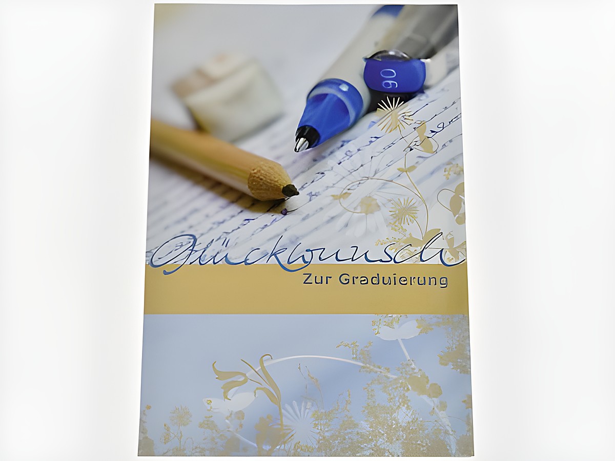 Auf dem Bild ist eine Glückwunschkarte zur Graduierung zu sehen, umgeben von Stiften und einem Schreibblock. Die Karte zeigt eine elegante Schrift und florale Motive.