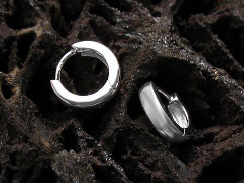 Elegante Creolen aus 925 Sterling Silber für Kinder, hergestellt von Juwelier Harnisch, liegen auf einer dunklen, strukturierten Oberfläche und strahlen zeitlosen Charme aus.