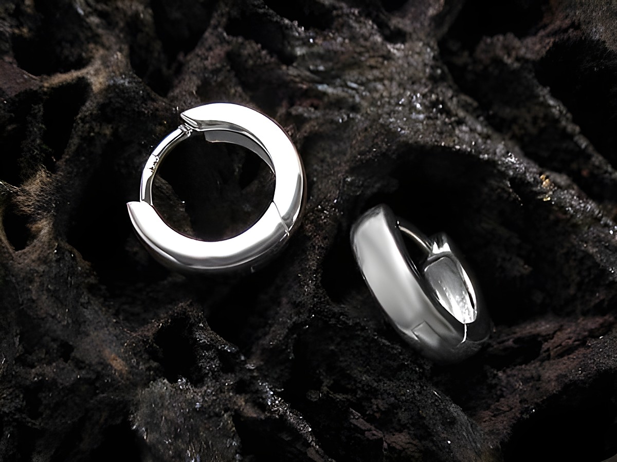 Elegante Creolen aus 925 Sterling Silber für Kinder, hergestellt von Juwelier Harnisch, liegen auf einer dunklen, strukturierten Oberfläche und strahlen zeitlosen Charme aus.