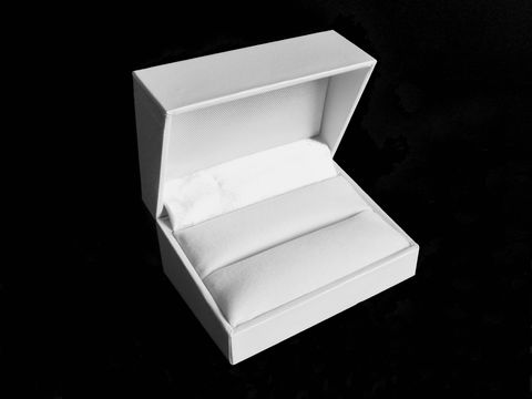 Geschenkschachtel für Trauringe und Manschettenknöpfe in klassischem Weiß, hergestellt von Juwelier Harnisch, öffnet sich und zeigt weiche Polsterung im Inneren zur sicheren Präsentation.