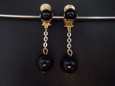 Schwarze Ohrclips mit goldfarbenen Elementen und Kunstharz. Zeitloses Design von Juwelier Harnisch, ideal für elegante Anlässe.