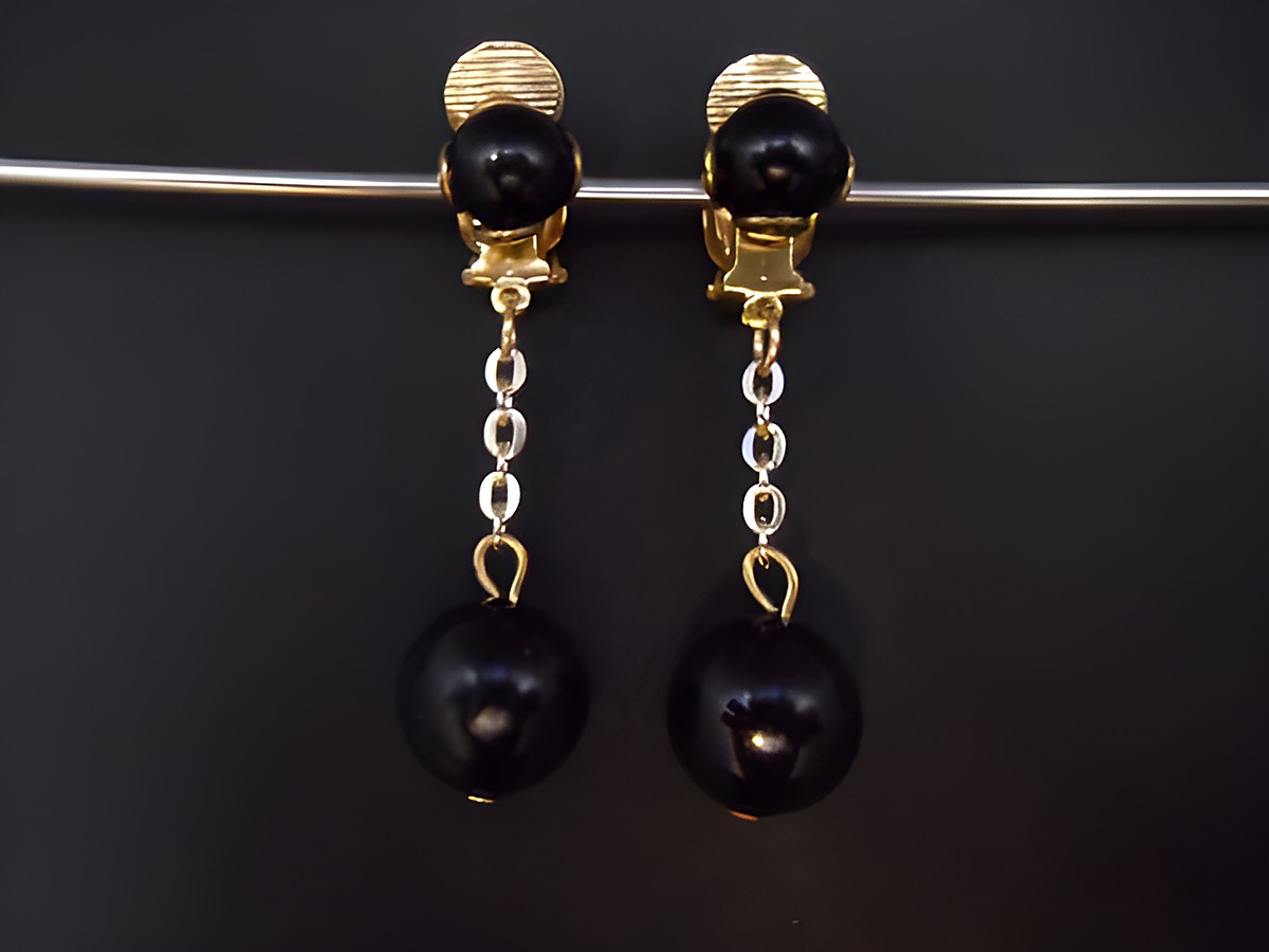 Schwarze Ohrclips mit goldfarbenen Elementen und Kunstharz. Zeitloses Design von Juwelier Harnisch, ideal für elegante Anlässe.