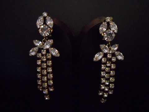 Goldfarbene, nostalgische Strass Ohrclips von Juwelier Harnisch mit eleganten, hängenden Buchstaben und funkelnden Strasssteinen, perfekt für besondere Anlässe.