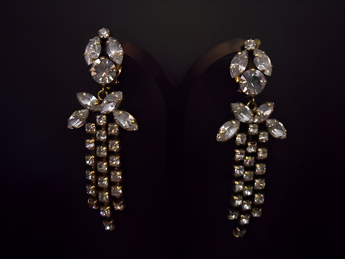 Goldfarbene, nostalgische Strass Ohrclips von Juwelier Harnisch mit eleganten, hängenden Buchstaben und funkelnden Strasssteinen, perfekt für besondere Anlässe.