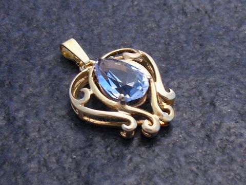 Glamouröser Goldanhänger mit einem synthetischen Aquamarin in tropfenförmiger Fassung, umgeben von filigranen, geschwungenen Elementen, Hersteller Juwelier Harnisch.
