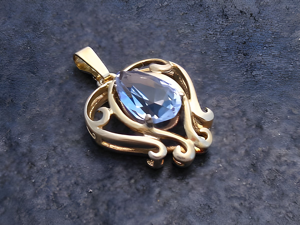 Glamouröser Goldanhänger mit einem synthetischen Aquamarin in tropfenförmiger Fassung, umgeben von filigranen, geschwungenen Elementen, Hersteller Juwelier Harnisch.