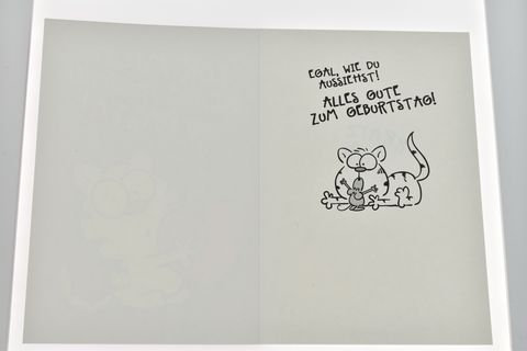 Geburtstagskarte mit einer lustigen gezeichneten Katze, die ein Herz hält. Innen steht eine fröhliche Geburtstagsbotschaft von Juwelier Harnisch. Ideal für Tierliebhaber.