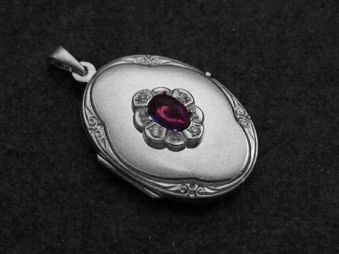 Amethyst lila Medaillon Cabochon aus Sterling Silber mit Brillanten, ausgestellt auf einem dunklen Untergrund. Das geschwungene Design und die edlen Materialien verleihen dem Schmuckstück einen eleganten Eindruck.