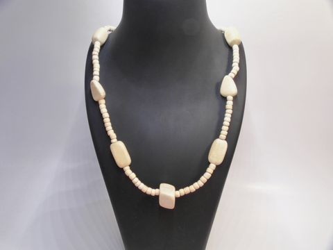 Holzkette Multiform 23 mm naturbraun 60 cm Holz Schmuck von Juwelier Harnisch, besteht aus verschiedenen holzfarbenen Perlen in unterschiedlichen Formen, elegant präsentiert auf einem Halter.