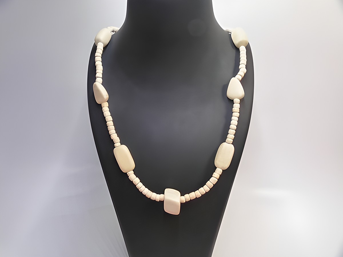Holzkette Multiform 23 mm naturbraun 60 cm Holz Schmuck von Juwelier Harnisch, besteht aus verschiedenen holzfarbenen Perlen in unterschiedlichen Formen, elegant präsentiert auf einem Halter.