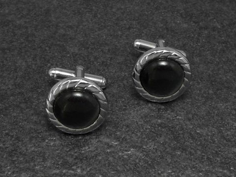 10447-0 Manschettenknöpfe in grau mit einem besonderen Design von 17 mm Durchmesser, silberfarben mit einer runden, dunklen Einlage, hergestellt von Juwelier Harnisch.