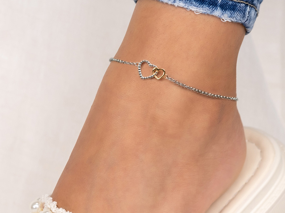 Elegante Fußkette aus Edelstahl in Bicolor-Design mit zwei Herzen. Sie hat eine Länge von 22 cm plus 5 cm Verlängerung und verleiht jedem Look eine romantische Note.