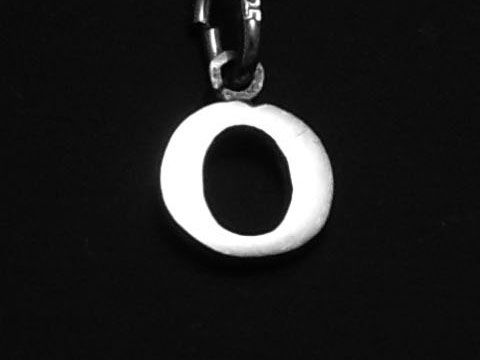 925 Sterling Silber Druck-Buchstaben Anhänger in Form des Buchstabens O, hergestellt von Juwelier Harnisch, glänzende Oberfläche auf schwarzem Hintergrund.