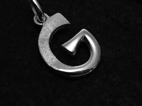 Ein teilmattierter Buchstabenanhänger G aus Sterling Silber des Juweliers Harnisch, elegant mit geschwungenen Formen und glänzenden Oberflächen.