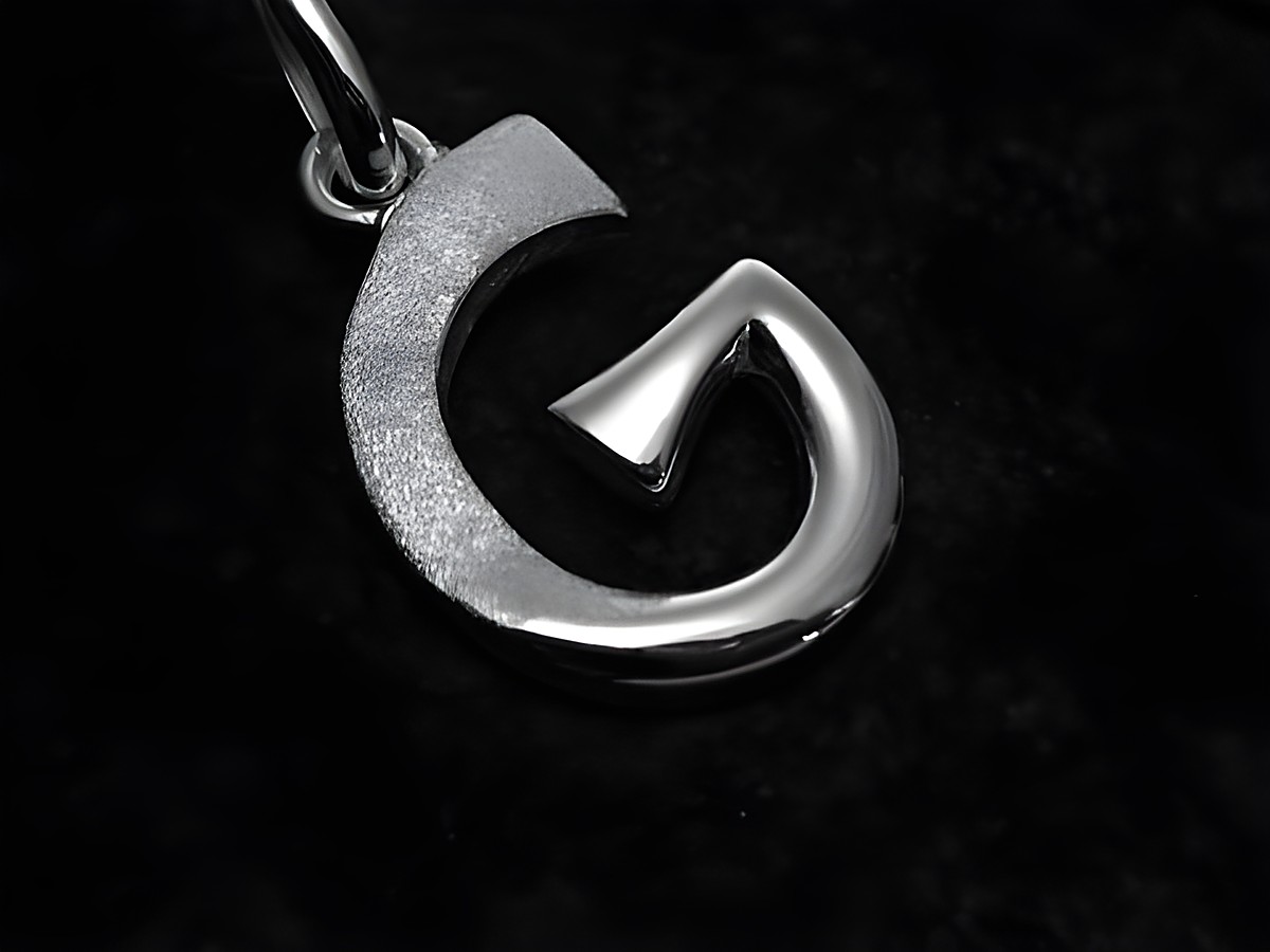 Ein teilmattierter Buchstabenanhänger G aus Sterling Silber des Juweliers Harnisch, elegant mit geschwungenen Formen und glänzenden Oberflächen.