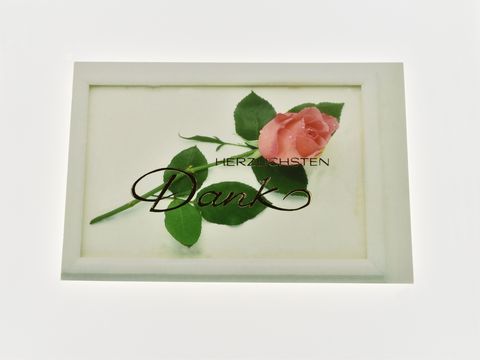 Eine Dankeskarte mit der Aufschrift Herzlichen Dank, dekoriert mit einer einzelnen rosa Rose und grünen Blättern, hergestellt von Juwelier Harnisch.