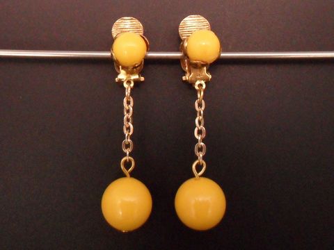 Gelbe zeitlose Ohrclips aus Kunstharz mit goldfarbener Befestigung und einer eleganten Kette, Hersteller Juwelier Harnisch, ideal für jeden Anlass.