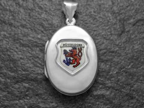Silbermedaillon mit dem Stadtwappen von Düsseldorf, das einen roten Löwen und ein blaues Schwert zeigt. Hersteller ist Juwelier Harnisch aus Nordrhein-Westfalen.