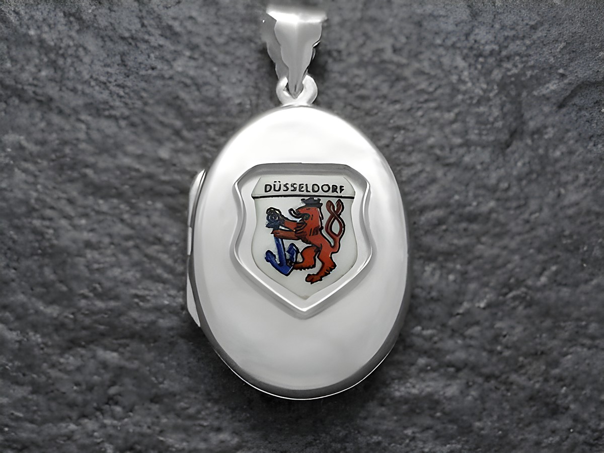 Silbermedaillon mit dem Stadtwappen von Düsseldorf, das einen roten Löwen und ein blaues Schwert zeigt. Hersteller ist Juwelier Harnisch aus Nordrhein-Westfalen.