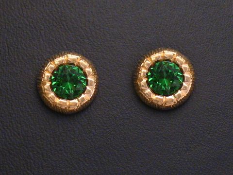 Ohrringe mit grün facettierten Stein in goldenen Ohrsteckern des Herstellers Juwelier Harnisch, umrandet von weiteren funkelnden Steinen.