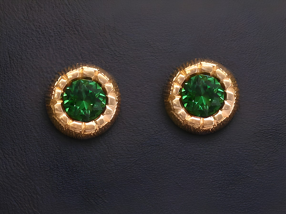 Ohrringe mit grün facettierten Stein in goldenen Ohrsteckern des Herstellers Juwelier Harnisch, umrandet von weiteren funkelnden Steinen.