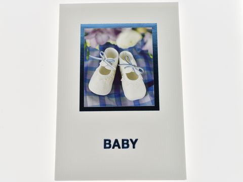 Glückwunschkarte mit Bild von eleganten Babyschuhen in Weiß und blauer Schleife, umgeben von blühenden Motiven, Hersteller Juwelier Harnisch, ideal zur Geburt.